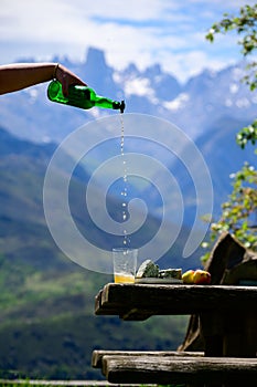 Pouring from high height of natural Asturian cider made fromÂ fermented apples, Asturian cabrales cow blue cheese with view on